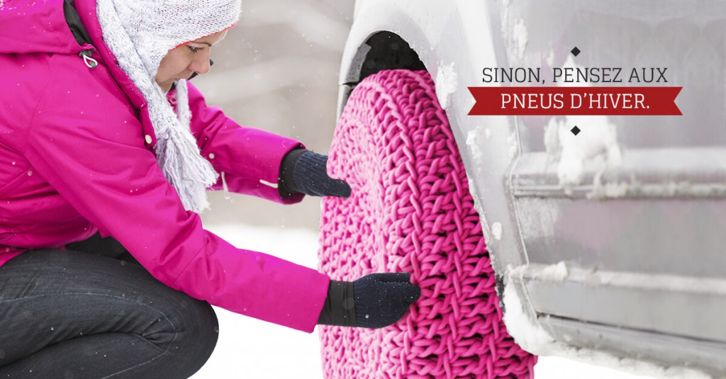 femme accroupie dans la neige installe une protection en laine rose sur une roue de voiture